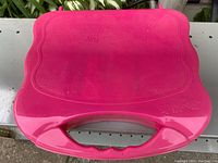 Closed pink plastic box with handle, embossed with brand information.