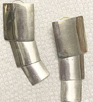 Pair of silver earrings with three linked rectangular, slightly curved components, showing their varying lengths and brushed finish.