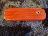 Closed rectangular wooden case with reddish wood grain and polished finish
