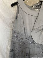 Photo of grey sleeveless dress with bead embellishments on waist and matching bolero jacket.