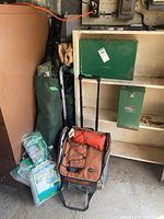 Photo of camping chairs, stools, cooler bag, and green metal boxes on garage shelving