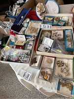 Overview of costume jewelry items on table including brooches, necklaces, earrings, rings and watch accessories
