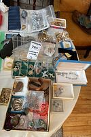 Overview of assorted costume jewelry on table including boxes, bags, and display slots showing brooches, necklaces, and other pieces.