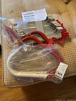 Photo showing the folded emergency escape ladder with red rubber-coated hooks and silver metal steps.