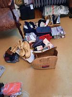 Overview of assorted ladies accessories laid on floor including handbags, gloves, wallets, shoes, and fabric items.