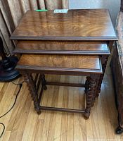 Stacked view of three nesting tables showing the wood grain tops and carved spiral legs