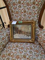 Overall view of first framed winter landscape painting on patterned chair