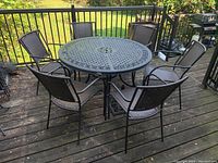 Overall view of round metal table with six stacking chairs on a deck with railing