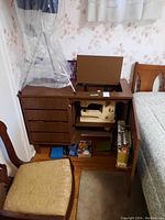 Full view of wood sewing cabinet with four drawers on left, cupboard door on right open showing cream-colored Bernina sewing machine inside.