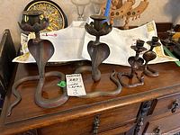 Front view of two 8" and two 5" painted metal snake candleholders on wooden surface