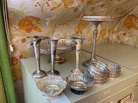 Overall view of three candlesticks, pierced serving bowl, compote stand, stack of coasters and appetizer bowls