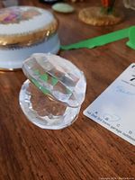 Clear, faceted Swarovski crystal heart paperweight resting on a wooden surface, showing shape and clarity from different angles.