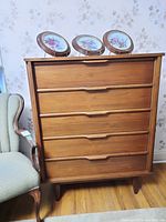 Front view of mid-century modern style tall teak dresser with five drawers and integrated pull handles, scratches on surface visible
