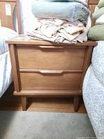 Front view of teak nightstand showing two drawers and wooden handles.