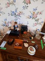 Overview of all items on wooden surface including figurine, boxes, ashtray, stones and small cabinet