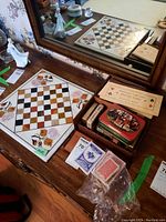 Top angled view of the stone chess board on a wooden dresser with multiple playing card decks, coasters, an official Contract Bridge count sheet, and a decorative container arranged to the side.