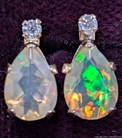 Close-up front view of the pear-shaped opal and moissanite stud gold earrings with visible internal opal coloration and round moissanite stones on top.