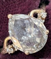 Close-up view of pear-cut center stone and side diamonds against fabric background