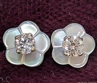 Two earrings displayed on dark fabric with front view