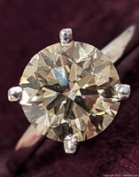 Top down close-up of round diamond showcasing facets and four-prong setting against dark background