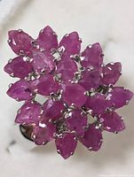 Close-up photo of the ring front showing pear-shaped ruby cluster and sterling silver prong settings.