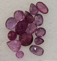 Close-up photo of multiple genuine ruby gemstones of varying sizes and cuts, showing their colors and some inclusions.