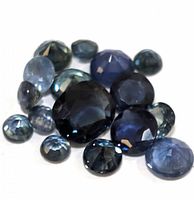 Close-up of 16 loose faceted genuine sapphire gemstones showing round and oval shapes in deep to lighter blue shades.