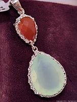 Close-up showing the reddish-orange faceted onyx stone and pale green chalcedony teardrop pendant with detailed sterling silver setting.