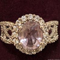 Close-up front photo showing oval faceted purple amethyst center surrounded by round clear cubic zirconia stones in sterling silver setting.