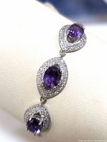 Close-up front diagonal view of the bracelet showing three pear-shaped amethysts surrounded by cubic zirconia in sterling silver setting on wrist display.