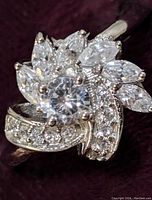 Close-up view of sterling silver ring showing clear round and marquise-shaped cubic zirconia stones forming a flower design with additional small stones on band swirl.