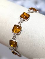 Close-up image showing bracelet links with square-shaped amber gemstones in silver bezels.