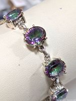 Close-up of three oval mystic topaz stones set in sterling silver with iridescent coloring