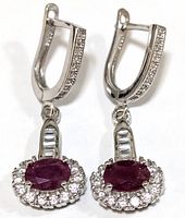 Front view of both sterling silver earrings showing the ruby center stones and cubic zirconia halo and baguette cut accents.