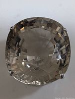 Close-up front view of the large cushion-cut smokey quartz pendant held by four prongs in a sterling silver setting showing the faceting details of the stone.