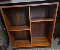 Front view of the medium sized wooden cabinet showing four openings and adjustable shelves inside.