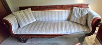 Full front view of wooden frame sofa with striped fabric upholstery and two toss pillows