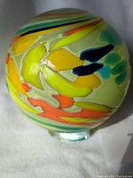 Close-up of the colorful blown glass globe showing detail of the vibrant pattern and glass texture.