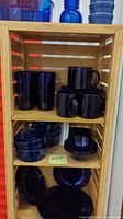 Shelves with cobalt blue mugs, tumblers, small bowls, and ramekins arranged.
