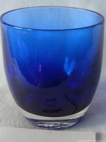 Blue glassybaby votive candle holder viewed front with visible blue transparent glass and clear thick base.