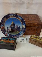 Decorative plate with Saint Isaac's Cathedral and surrounding landmarks, wooden jewelry box and lacquered box together in a single image.