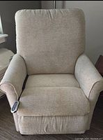 Front view of cream plush upholstered lift recliner chair with remote control on the left armrest.