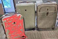 Three pieces of luggage: two hard-sided clamshells and one soft-sided bag, all with houndstooth pattern and showing signs of exterior scuffing, placed indoors on carpet