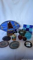 Photo showing full lot including stained glass sailboat, glass cat, various glass figurines and coasters.