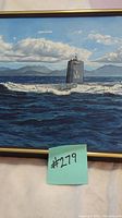 Frontal view of the framed oil painting of USS Swordfish submarine in ocean setting with land and clouds