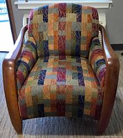 Full frontal photo of the upholstered armchair showing multicolored patchwork fabric and wooden armrests with visible wear and tear.