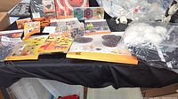 Wide view of Halloween items on black tablecloth showing treat cones, spiderweb, window clings, and figurines