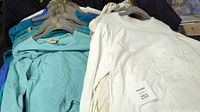 Group of ladies long sleeve tops in assorted colors, showing white, turquoise, and blue tops on hangers.