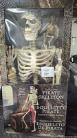 Front view of the packaged 60-inch poseable pirate skeleton showing the detailed bone structure and box art with the skeleton posed sitting.