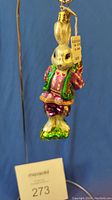 Front and side view of Radko Romeo Rabbit glass ornament hanging with visible Radko medallion tag.